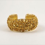 A gold bracelet with yellow stones on it.