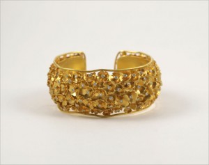A gold bracelet with yellow stones on it.