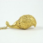 A gold necklace with a bird on it.