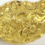 A close up of the gold leaf on the back of a brooch.