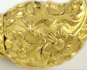 A close up of the gold leaf on the back of a brooch.