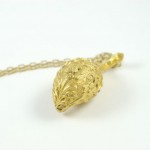 A gold necklace with a leaf shaped pendant.