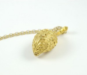 A gold necklace with a leaf shaped pendant.