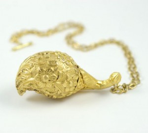 A gold necklace with a large object on it.