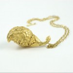 A gold necklace with a leaf shaped pendant.