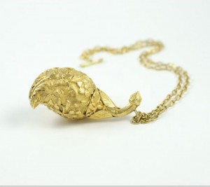 A gold necklace with a leaf shaped pendant.