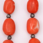 A close up of two necklaces with red beads