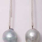 A pair of silver earrings with chains and pearls.