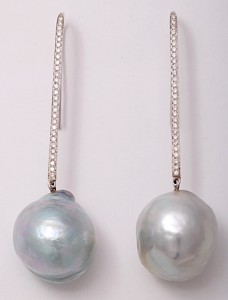 A pair of silver earrings with chains and pearls.