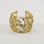 A gold bracelet with flowers and leaves on it.