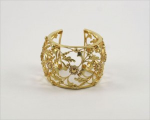 A gold bracelet with flowers and leaves on it.