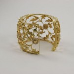 A gold bracelet with leaves and flowers on it.