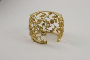 A gold bracelet with leaves and flowers on it.