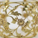 A close up of the gold bracelet with flowers and leaves