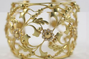A close up of the gold bracelet with flowers and leaves