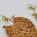 A pair of gold earrings with intricate designs.