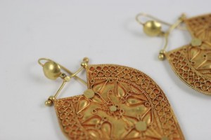 A pair of gold earrings with intricate designs.