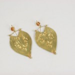 A pair of gold leaf earrings with a yellow stone.