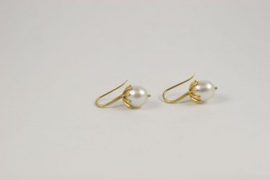 A pair of gold earrings with pearls on them.