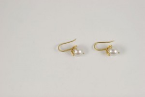 A pair of gold earrings with pearls on them.
