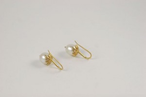 A pair of gold earrings with white pearls.