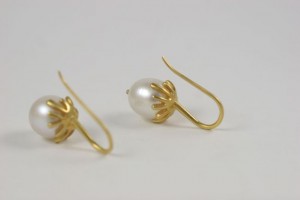 A pair of gold earrings with pearls on them.