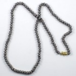 A long necklace of grey beads with gold clasp.