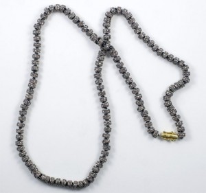 A long necklace of grey beads with gold clasp.