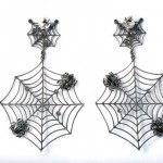 A pair of spider web earrings with spiders.