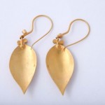 A pair of gold earrings with a leaf design.