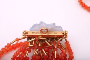 A close up of the clasp on an orange bead necklace.