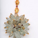 A gold necklace with a large flower shaped pendant.