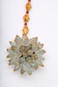 A gold necklace with a large flower shaped pendant.