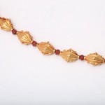 A gold chain with red stones on it.