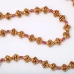 A close up of a necklace with pink beads