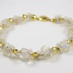 A bracelet with gold and white beads on it.