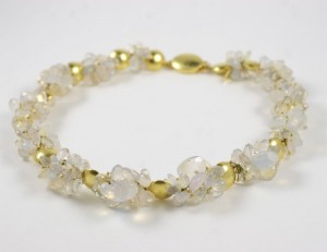A bracelet with gold and white beads on it.