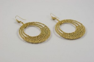 A pair of gold earrings sitting on top of a table.