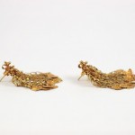 A pair of gold earrings with a bird on them.