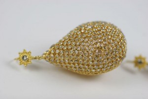 A gold and diamond earring is shown on top of the table.