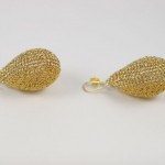 A pair of gold earrings sitting on top of a table.