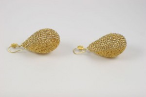 A pair of gold earrings sitting on top of a table.
