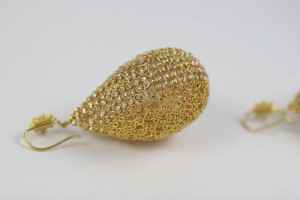 A pair of gold earrings with white stones.
