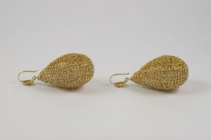 A pair of gold earrings sitting on top of a table.