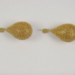 A pair of gold earrings sitting on top of a white surface.