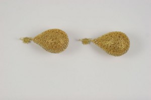 A pair of gold earrings sitting on top of a white surface.