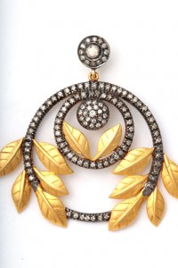 A gold and diamond earring with leaves hanging from the bottom.