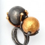 A black and gold ring with two balls on it