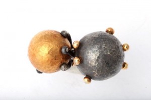 A gold and silver ball is sitting on top of another metal ball.