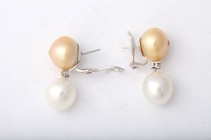 A pair of earrings with two pearls hanging from them.